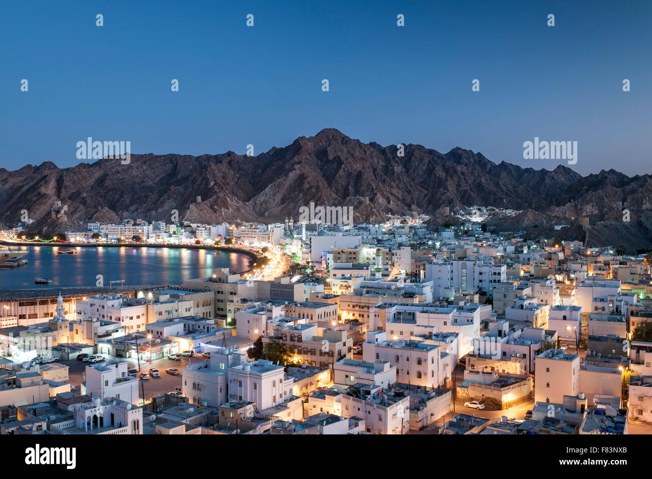 Abenddämmerung Blick auf den Stadtteil Mutrah und die umliegenden Berge in Muscat, der Hauptstadt des Sultanats Oman. Stockfoto