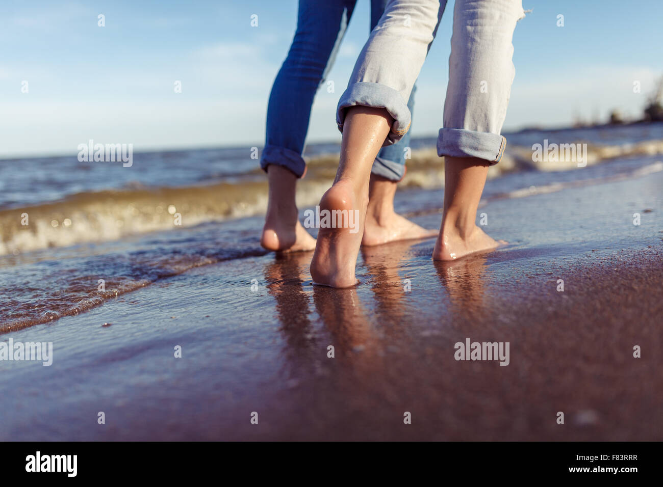Füße des Paares. Frau und Mann in den Wellen des Meeres auf dem sunset Stockfoto