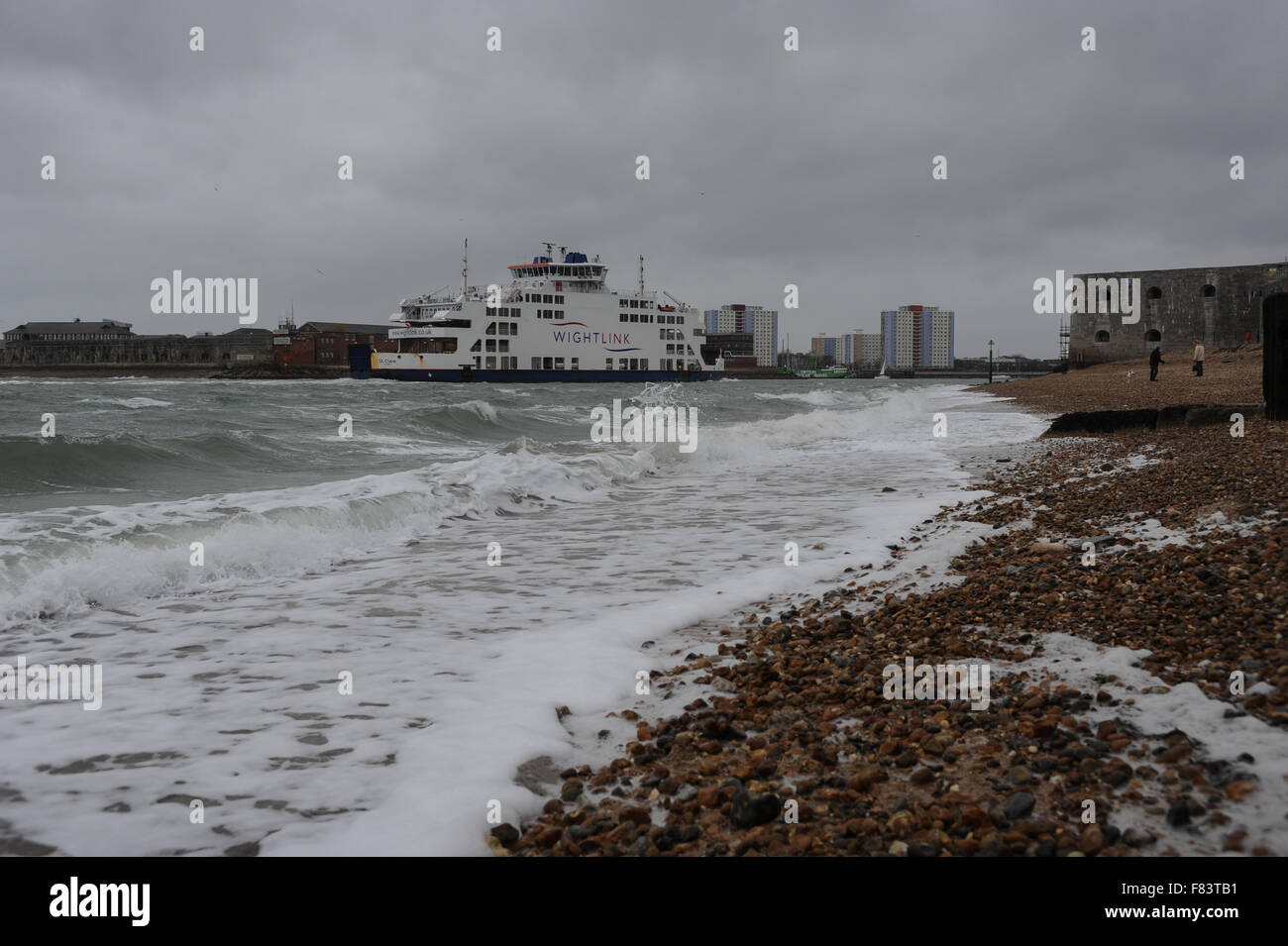 An einem stürmischen Tag Wellen auf den Strand als wightlink Fähren kommt in Portsmouth Harbour in Portsmouth, Hampshire, England. Stockfoto