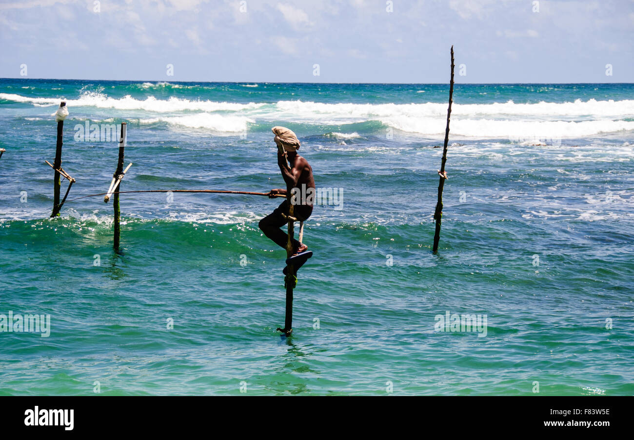 Fischer sitzt auf einem Mast, die Annahme der traditionellen Methode des Fischfangs in Sri Lanka Stockfoto