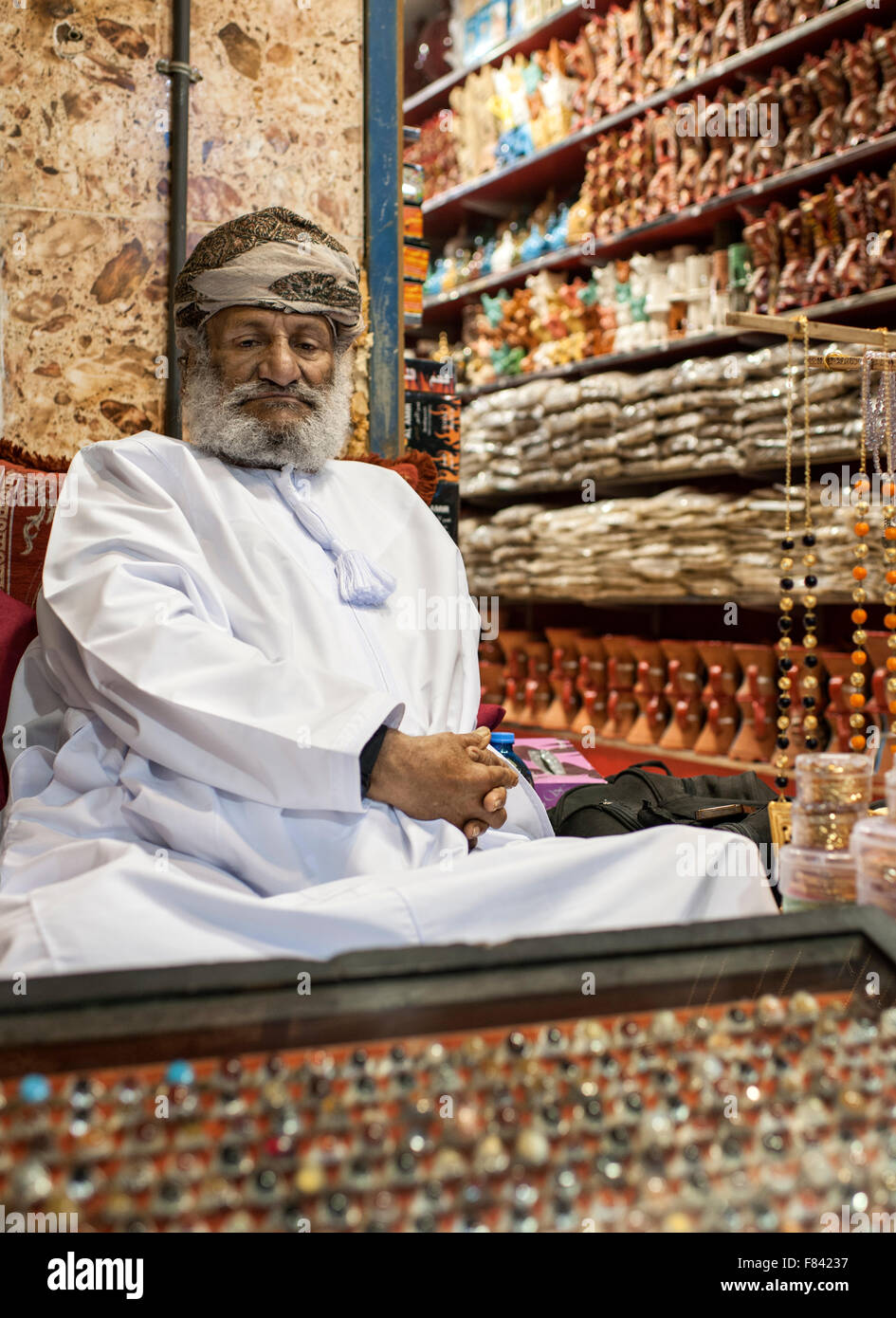 Omanische Mann sitzt vor seinem Geschäft in Mutrah Souk in Muscat, der Hauptstadt des Sultanats Oman. Stockfoto