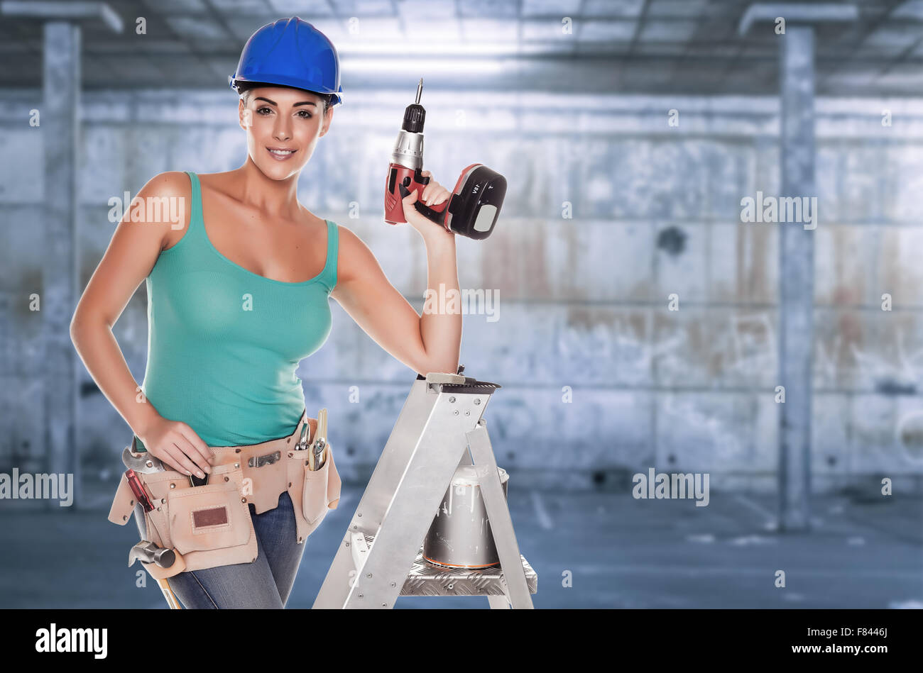 Weibliche Bauarbeiter auf einer Leiter über einem Grunge-Wand-Hintergrund. Stockfoto