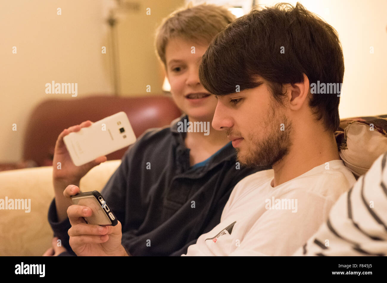 Drei gut aussehende weiße glücklich Jungs im Teenageralter Lachen und Blick auf ihre Handys, Online-Spiele, YouTube anschauen und auf soziale meida Stockfoto