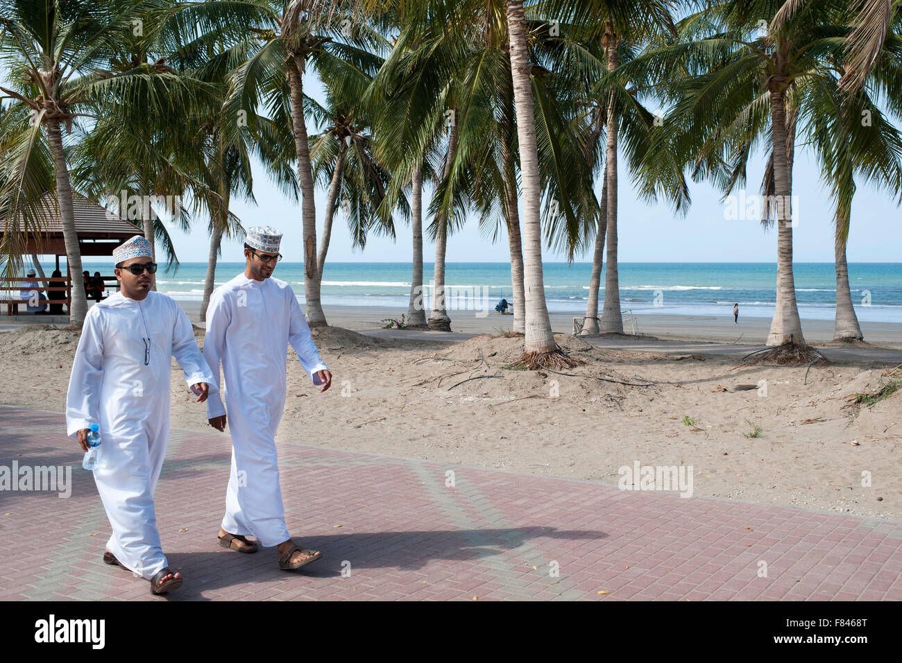 Zwei omanischen Männer zu Fuß entlang der Strandpromenade Qurum in Muscat, der Hauptstadt des Sultanats Oman. Stockfoto