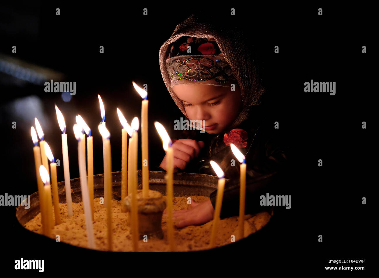 Ein junges orthodoxes Mädchen zündet eine Kerze an Kirche des Heiligen Grabes Christliches Viertel Altstadt Ost Jerusalem Israel Stockfoto