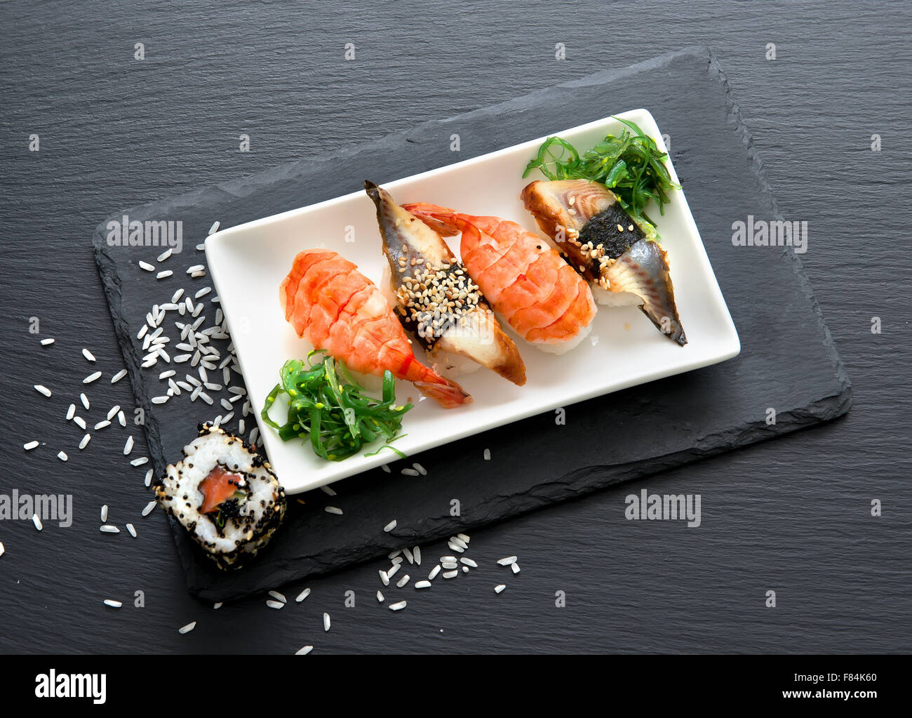 Sushi in Platte auf einem schwarzen Schiefer Tisch mit Salat Stockfoto