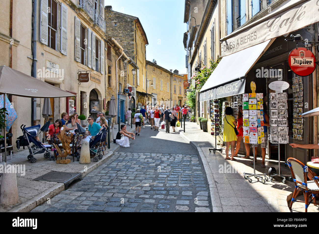 Lourmarin Dorf im Bereich Luberon Provence Touristen entspannen im Schatten an Freiluft-Café-Tischen in engen Straße Stockfoto
