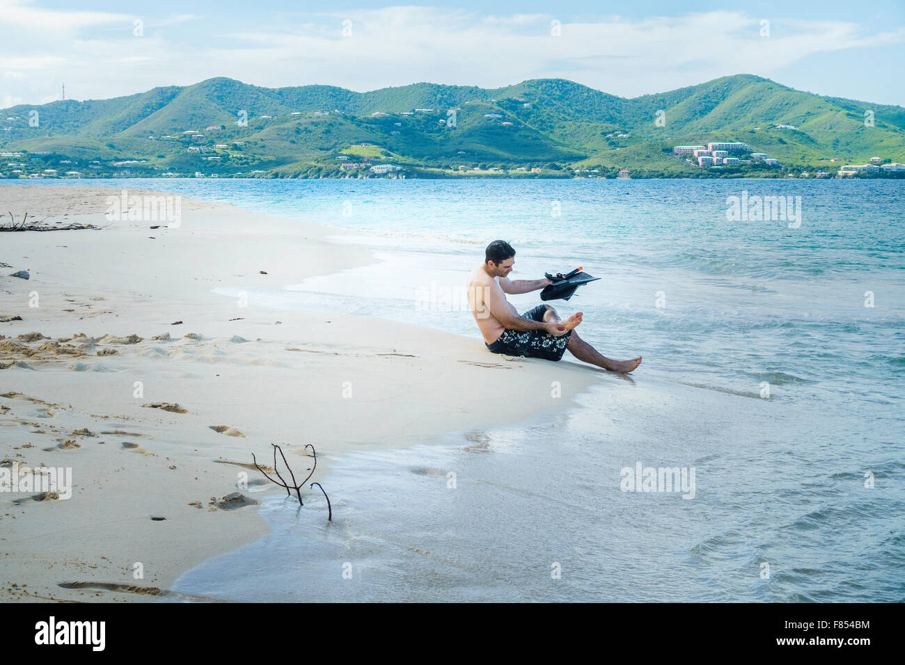 Ein kaukasischer Mann bereitet auf Schwimmen flossen vor dem Schnorcheln in der Karibik, am Turtle Beach, Buck Island, U.S.V.I. USVI. St. Croix Hintergrund. Stockfoto