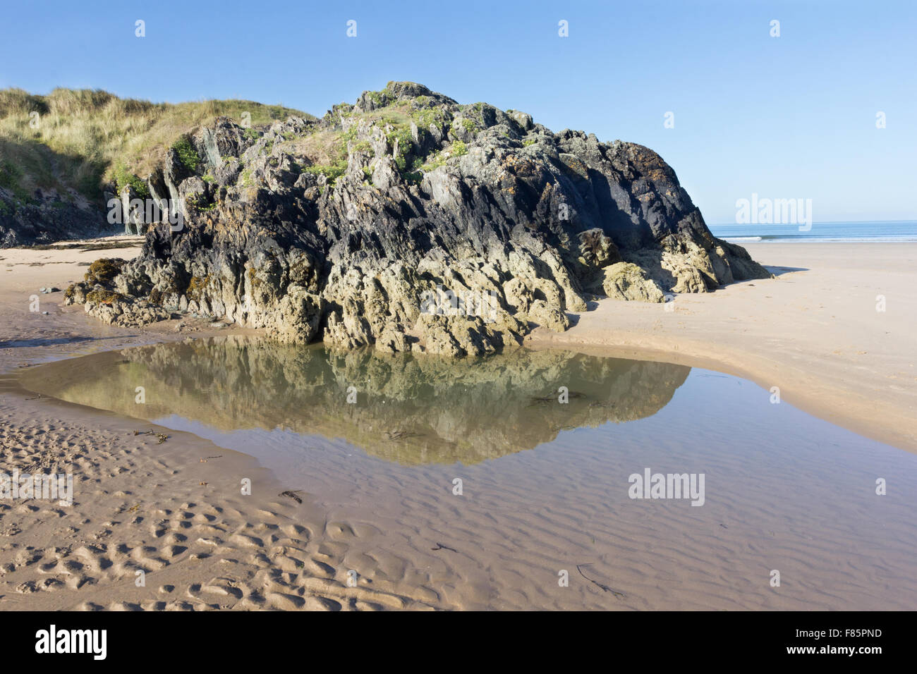 Vulkangestein und Pool am Strand Newborough, Anglesey, Wales Stockfoto