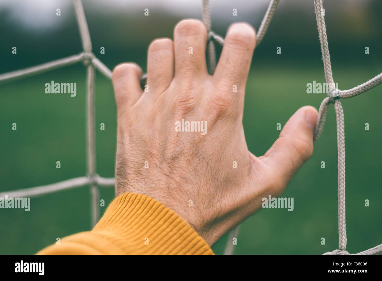 Männliche Hand Holding Fußballnetz, Retro getönt, selektiven Fokus Stockfoto