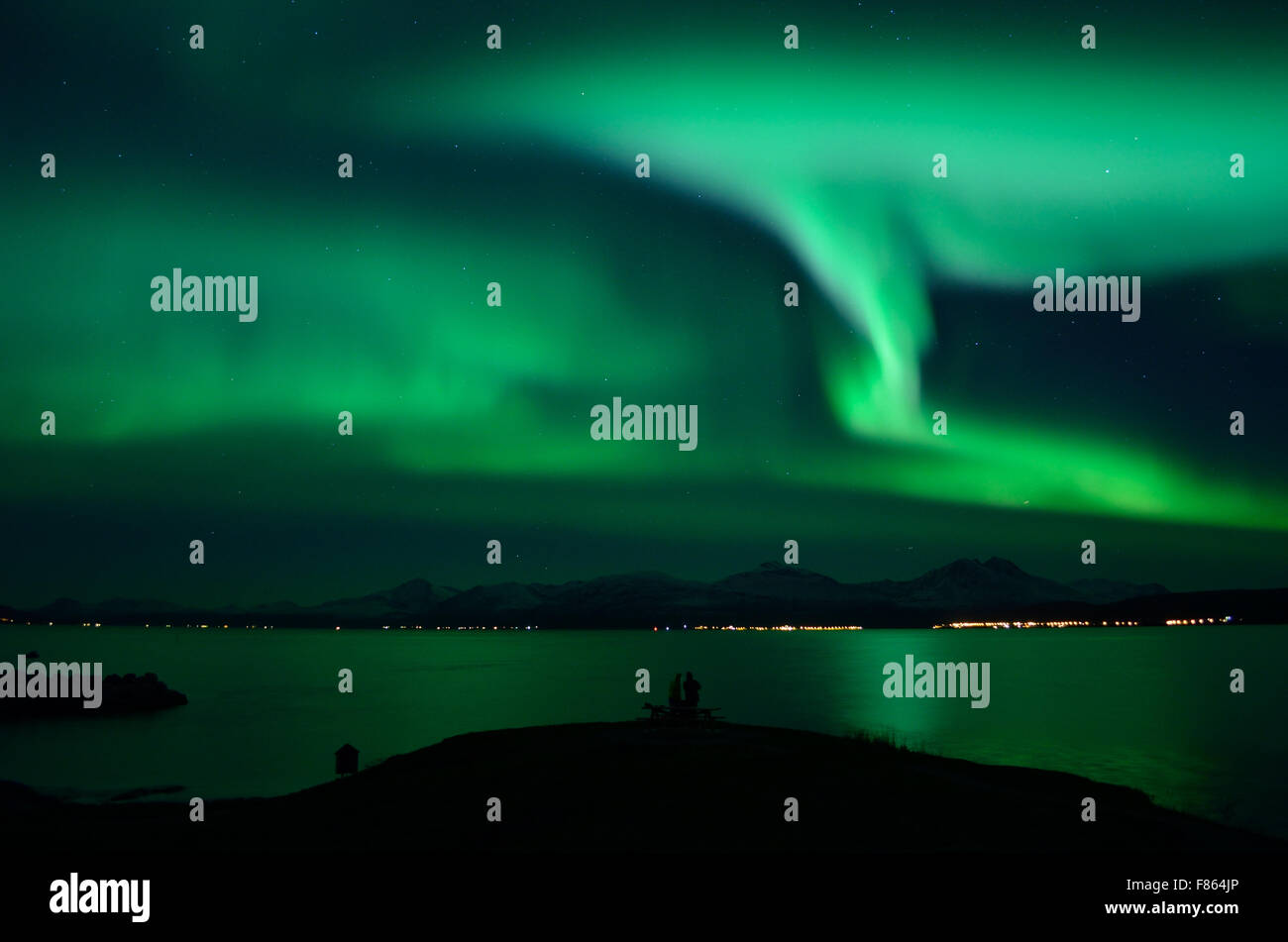 starkes Nordlicht auf Fjord und Berge mit Touristen vor Stockfoto