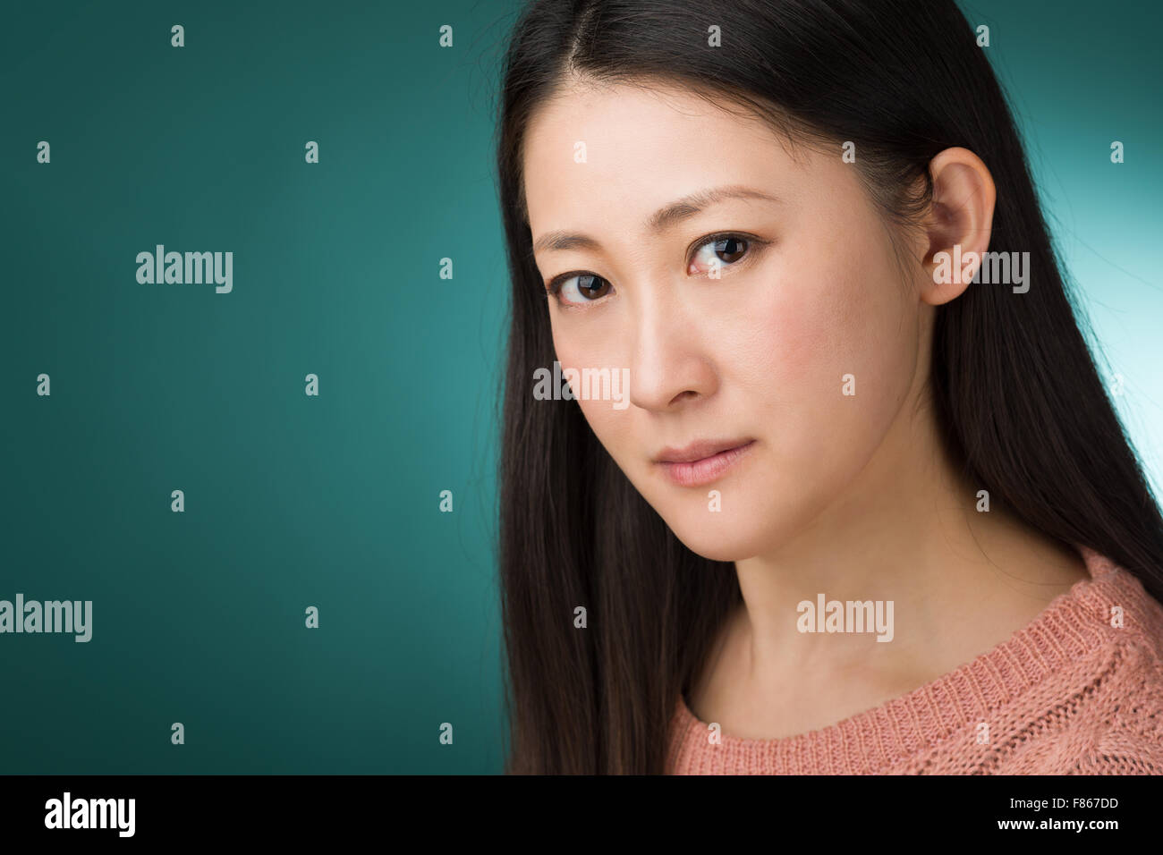 Ein Kopfschuss von einer Japanerin in hören Anfang der 30er Jahre auf einem grünen Hintergrund. Stockfoto