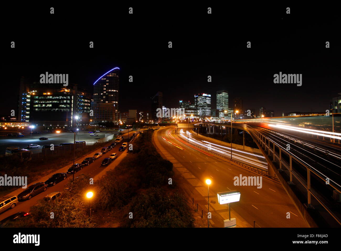 Londons Canary Wharf Financial District-Gebäude in der Nacht mit Autobahnverkehr und Docklands Light Railway (DLR) Stockfoto