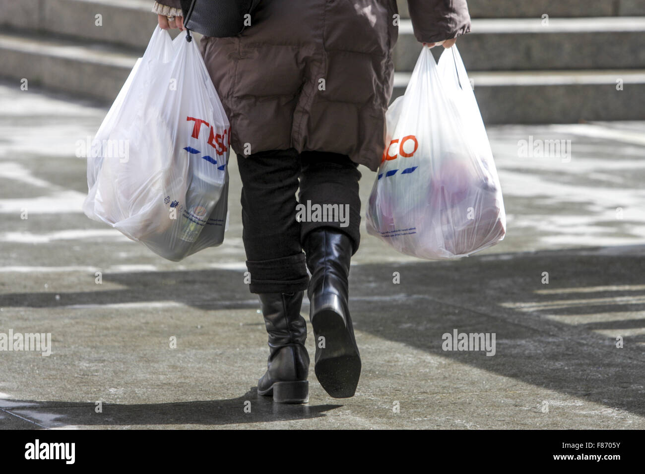 Kaufen Sie in Plastiktüten Tesco Bag Store, Einkaufstaschen aus dem Supermarkt Plastiktüten Frau gehen weg Stockfoto