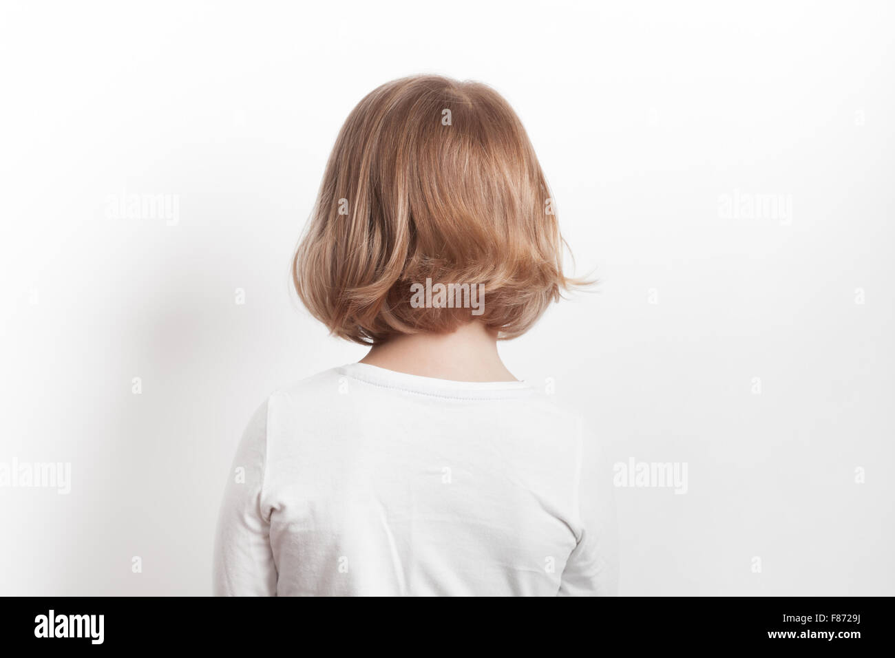 Kleine blonde kaukasische Mädchen Rückblick auf weißem Hintergrund, Studioportrait Stockfoto