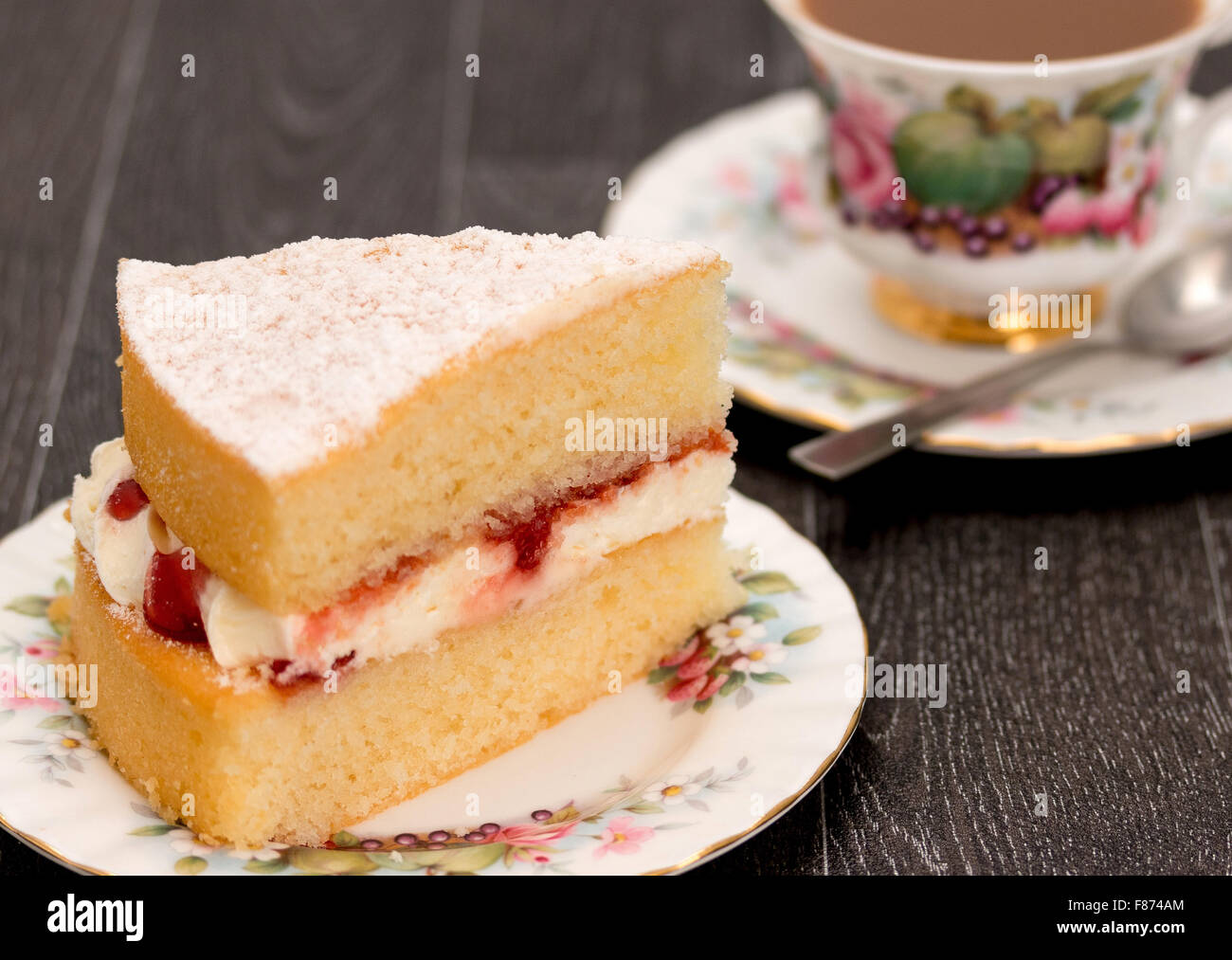 Ein Stück vom Victoria Schwammkuchen und eine Tasse Kaffee mit antiken reich verzierten Geschirr - Studio mit einer geringen Schärfentiefe erschossen Stockfoto