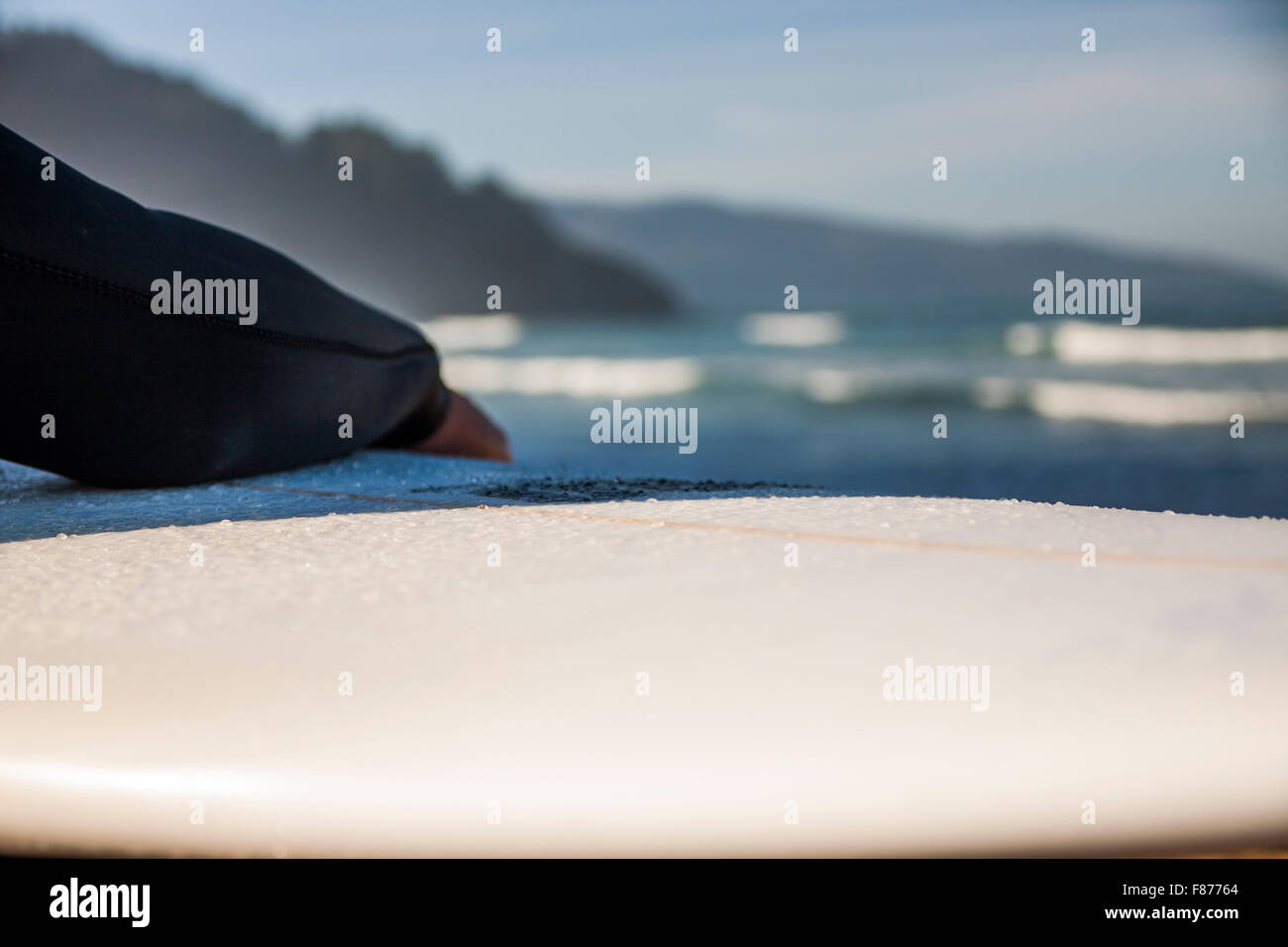 Surfer am Strand mit seinem Brett sitzen Stockfoto