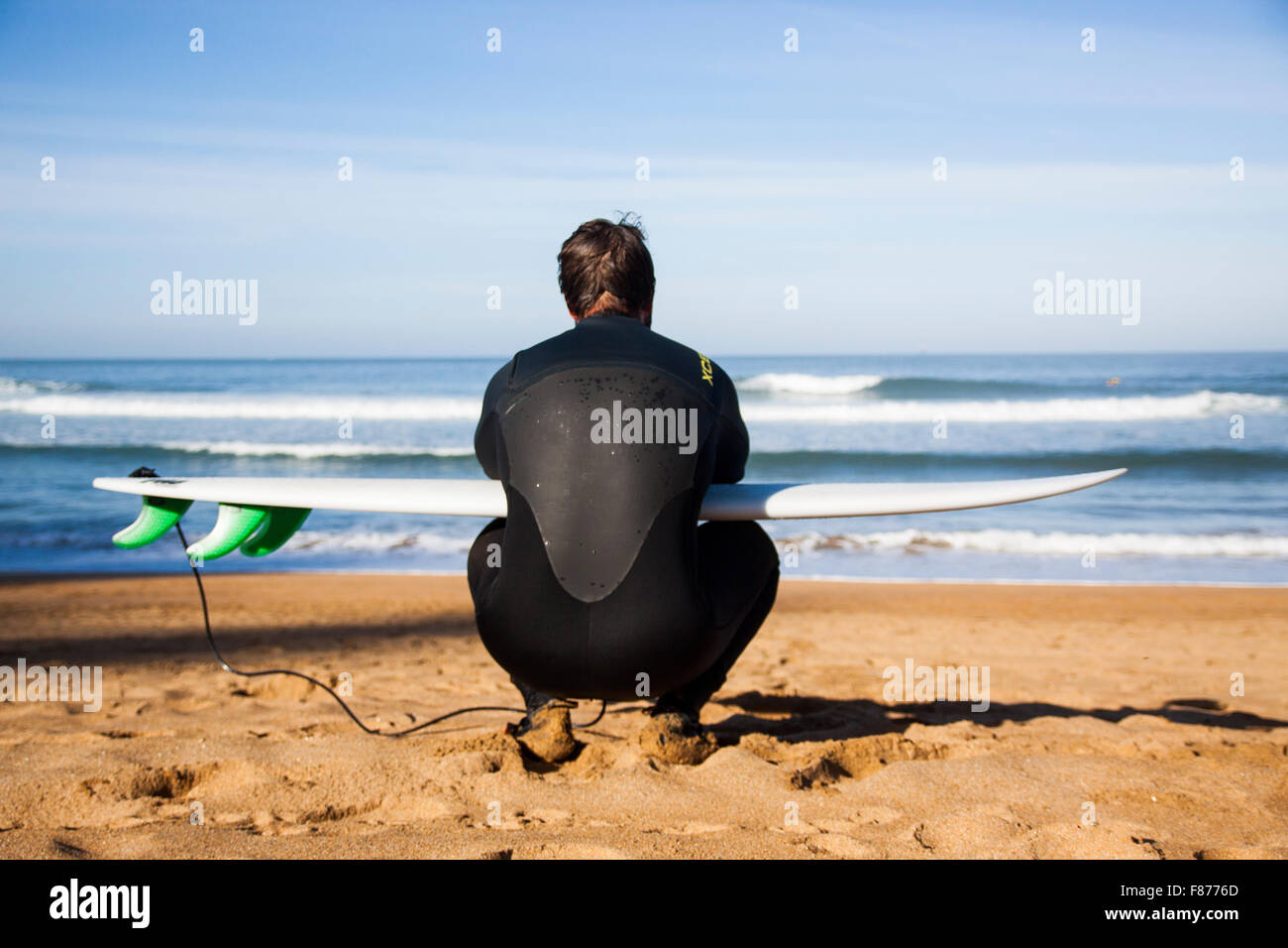 Surfer am Strand mit seinem Brett am Meer sitzen Stockfoto