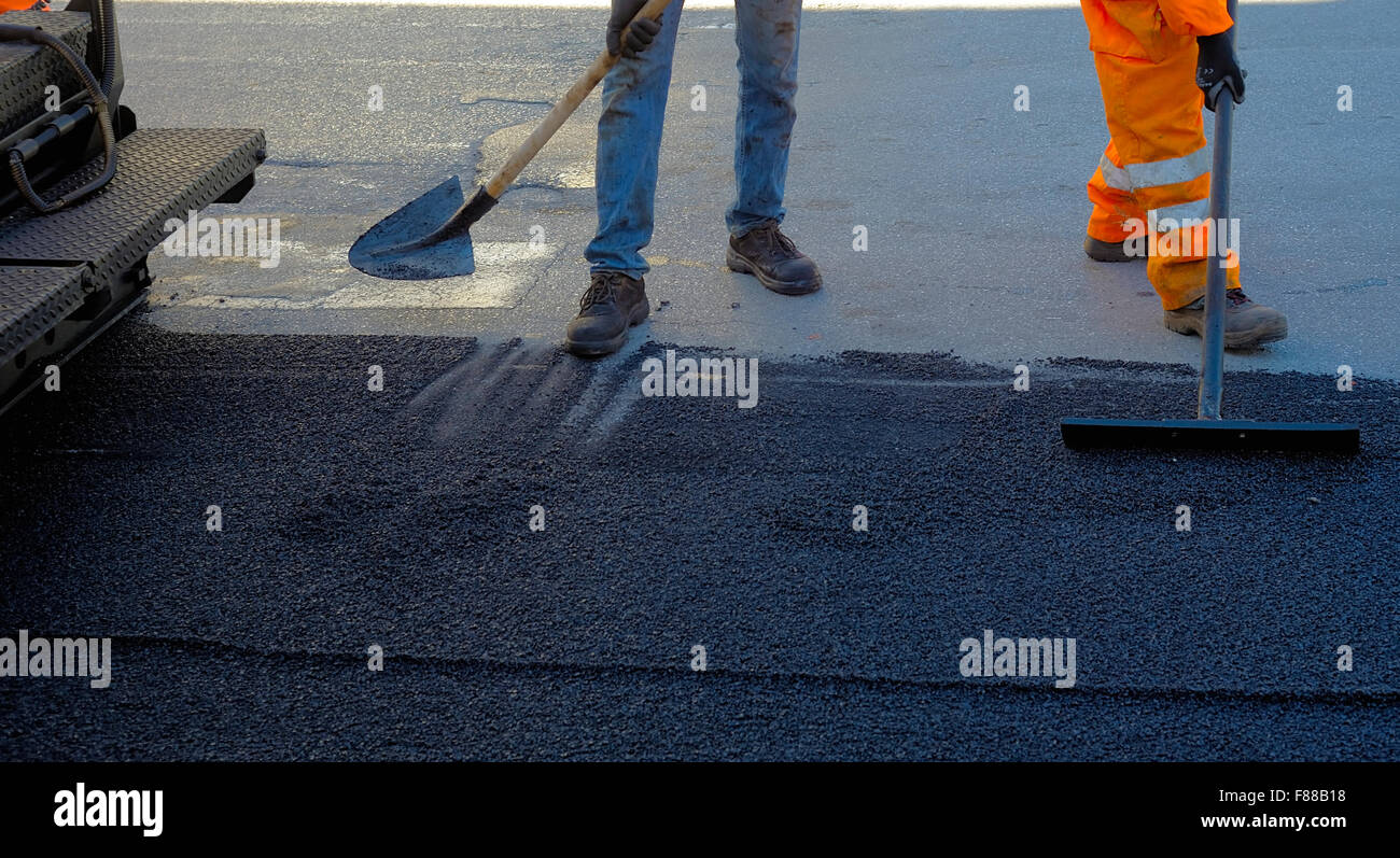 Bauarbeiter mit Schaufel während Asphaltierung Road Works Stockfoto