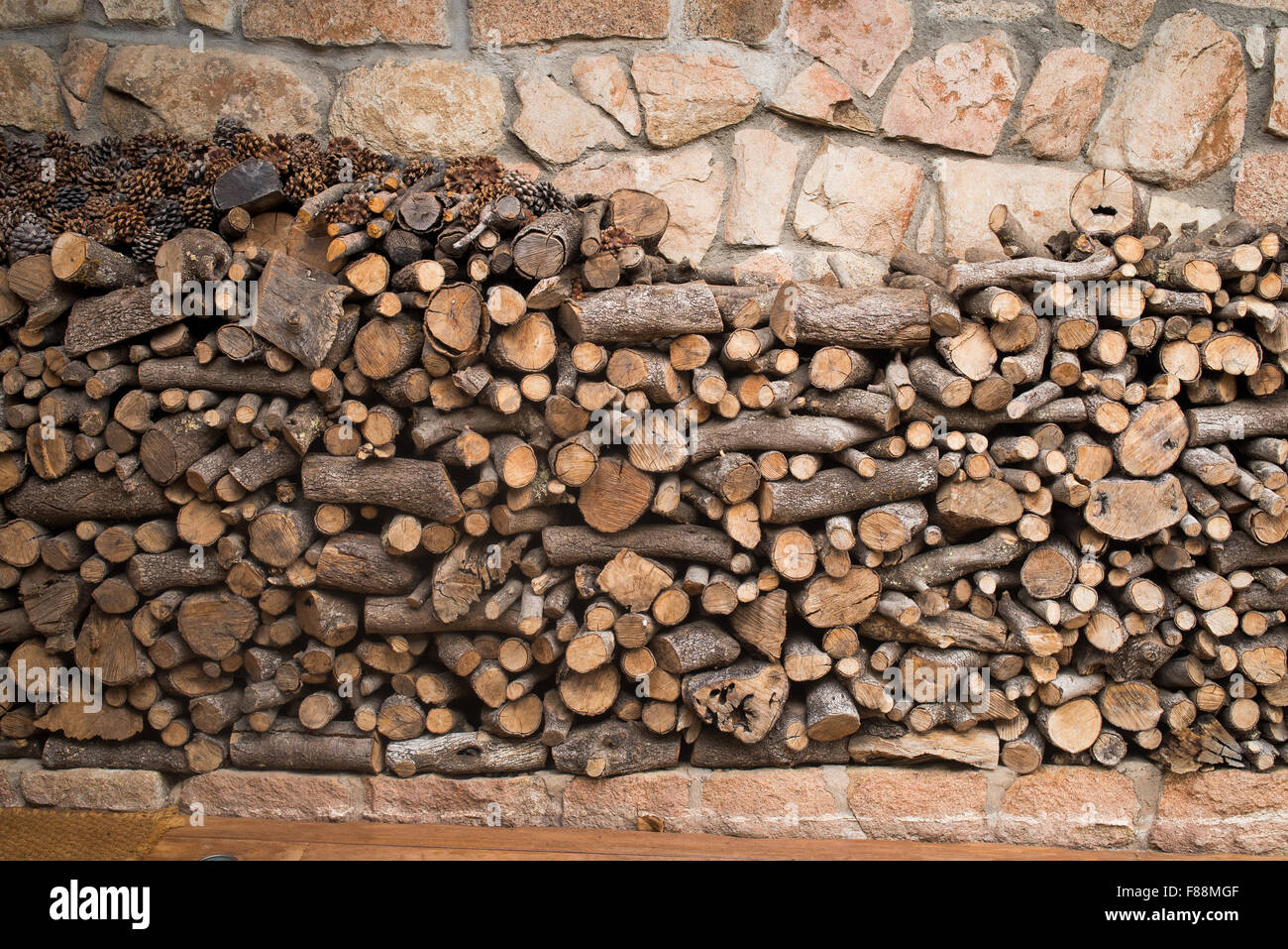 Große Haufen von Protokollen vorne eine Steinmauer. Stockfoto