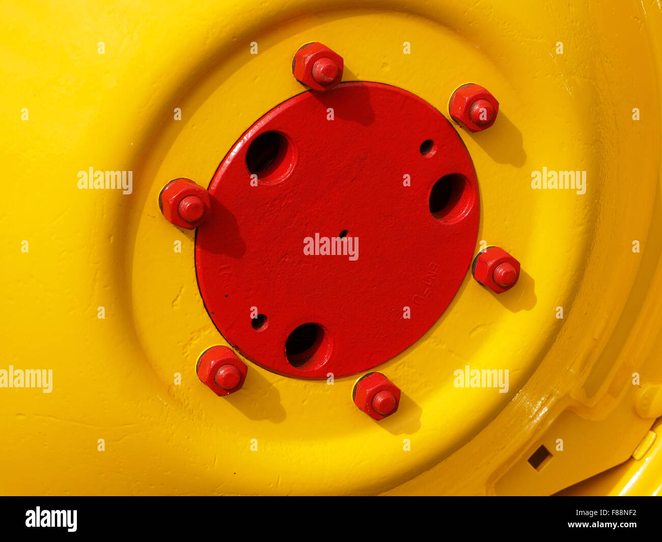 Detail des gelben klassische Traktor Rad mit roten Radmuttern und Bolzen bei strahlendem Sonnenschein Stockfoto