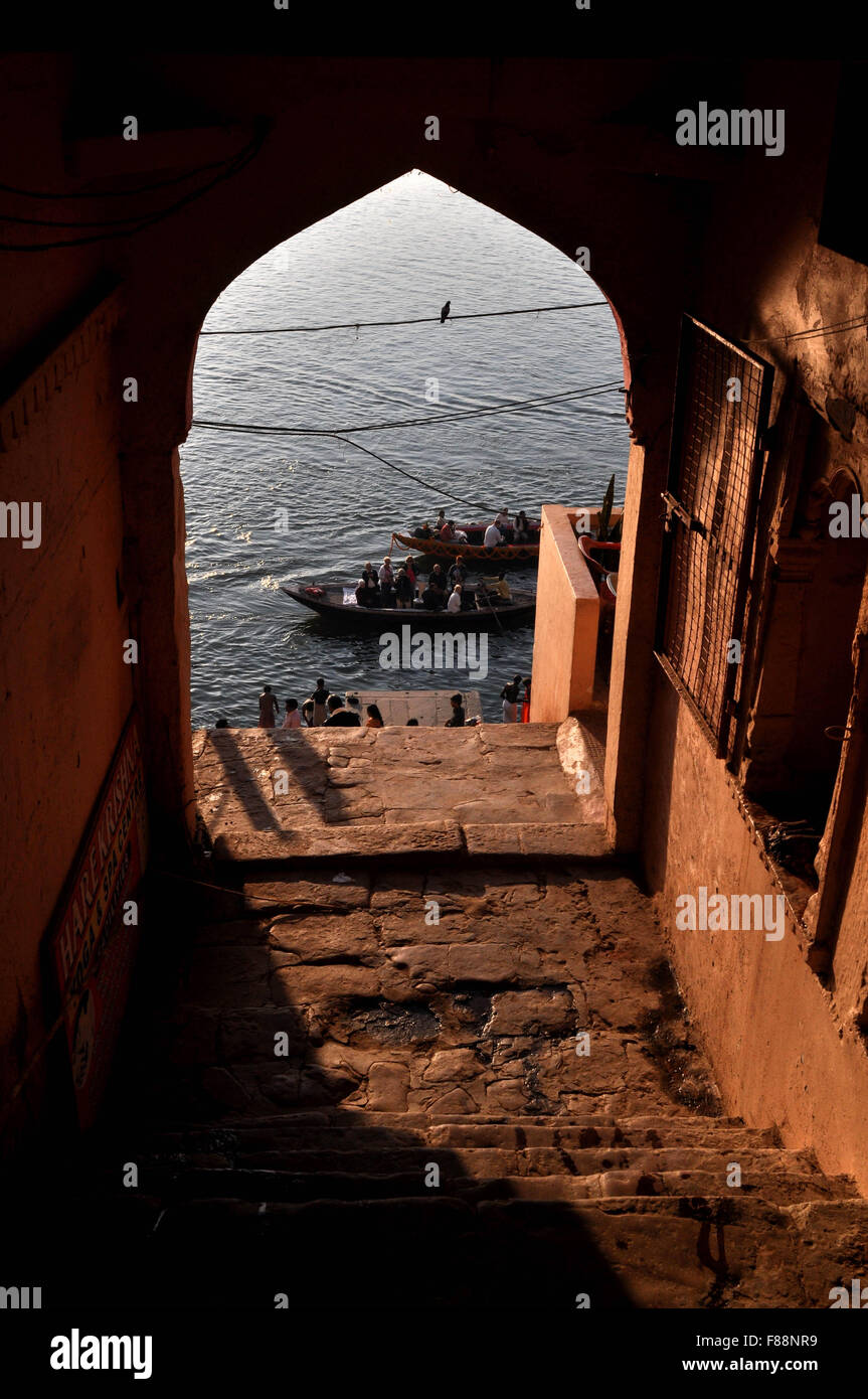 Blick aus einem alten Gebäude Tor einige Pilger mit Booten, um heiligen Fluss Ganges zu überqueren, an ihren Bestimmungsort in Varanasi Stadt erreichen. Stockfoto