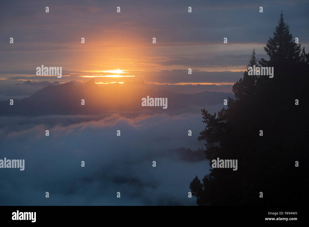 Sonnenuntergang im Dunst über den Wolken auf eine Wanderung durch die hohen Berge in den Schweizer Alpen zu sehen. Stockfoto