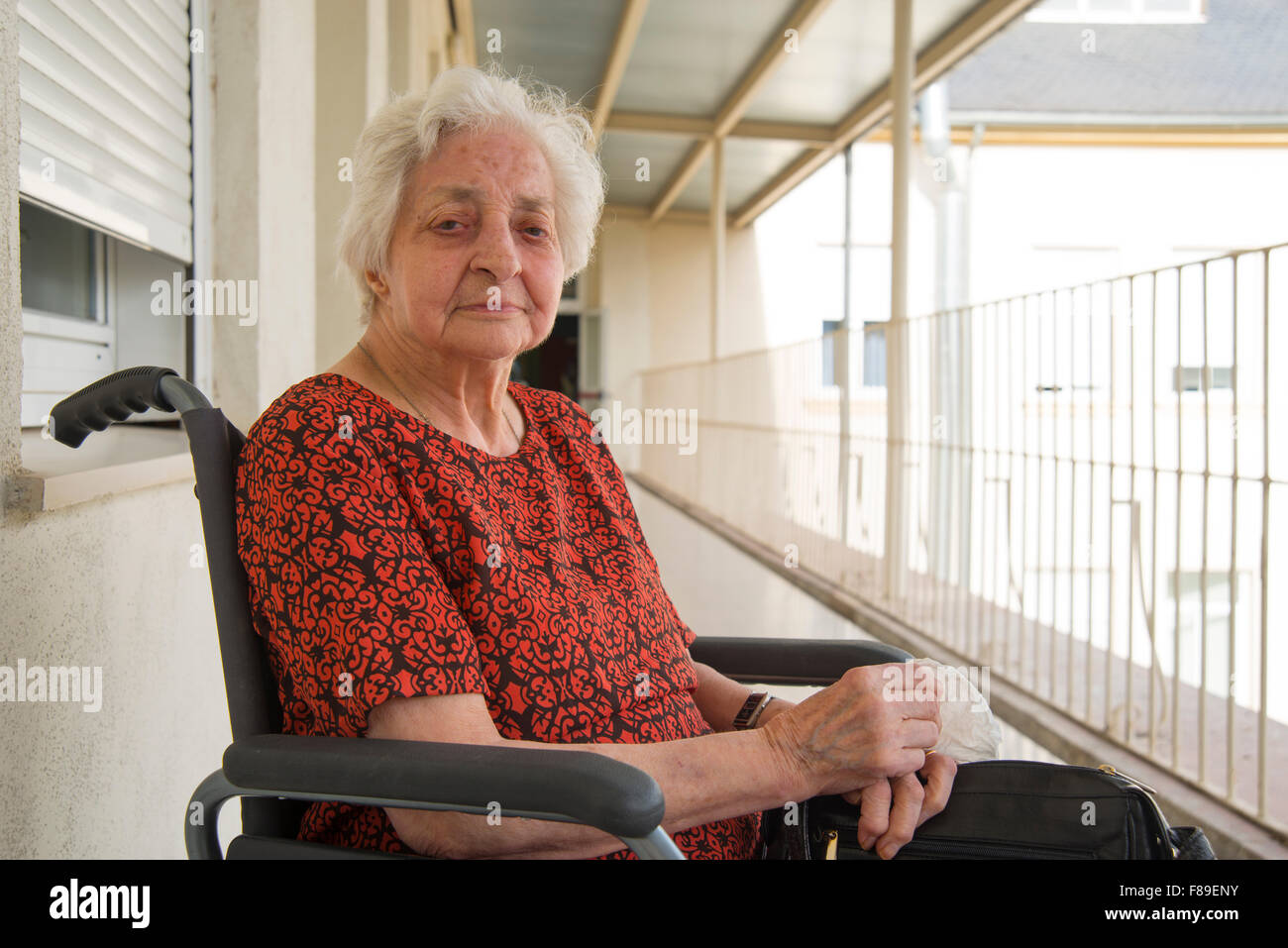 Porträt der Seniorin im Rollstuhl, auf der Terrasse eines Altenheims. Stockfoto