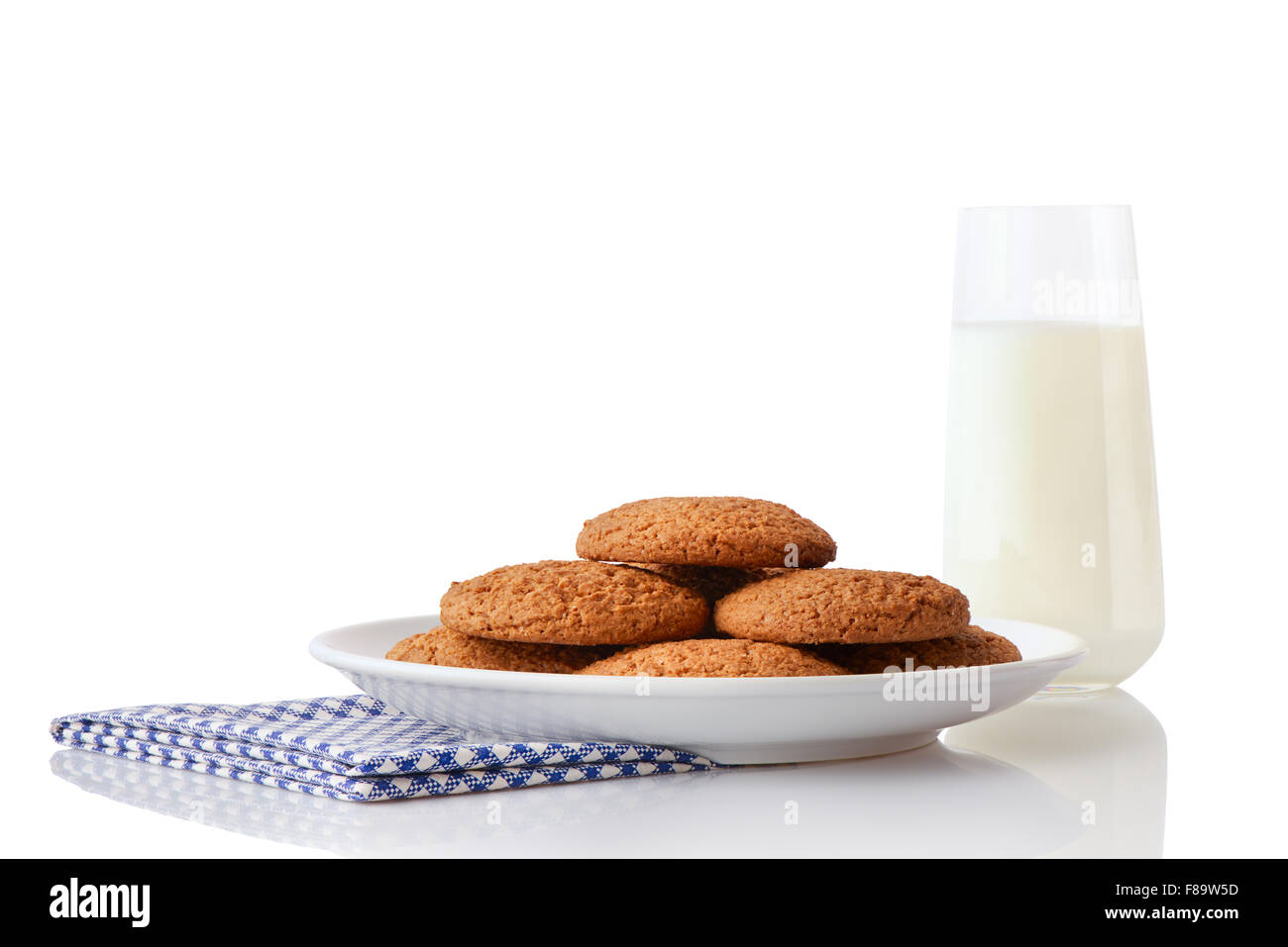 Haufen von hausgemachte Haferkekse auf weißen Keramikplatte auf blaue Serviette und ein Glas Milch, isoliert auf weißem Hintergrund Stockfoto