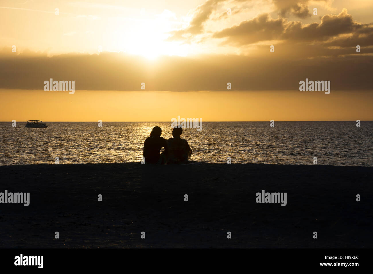 Ein paar einen goldenen Sonnenuntergang am Strand mit Sand Key, Clearwater, Florida, USA Stockfoto