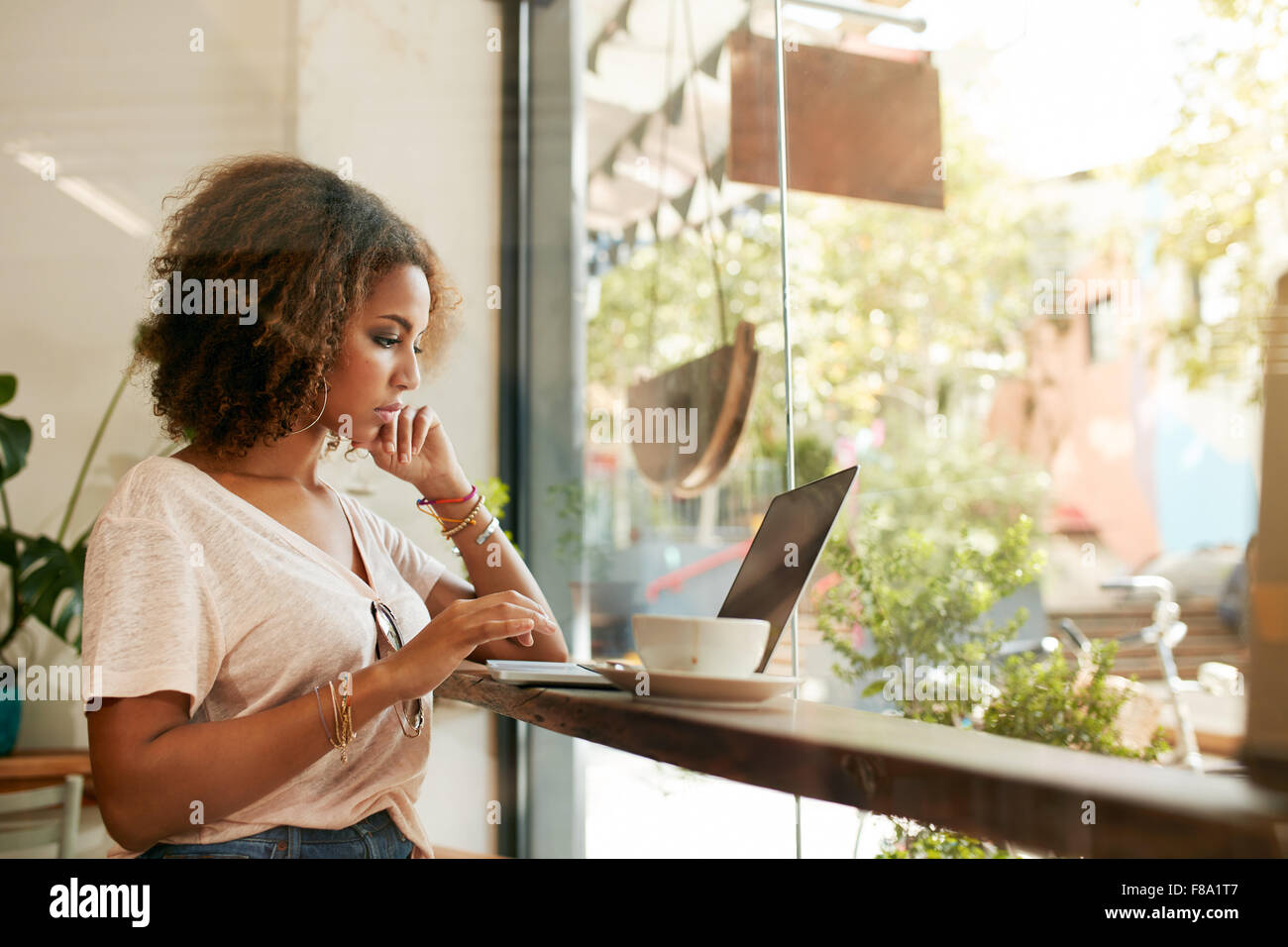 Junge schwarze Hündin im Café mit Laptop. Afrikanische junge Frau in einem Restaurant beschäftigt, arbeiten an ihrem Laptop sitzen. Stockfoto