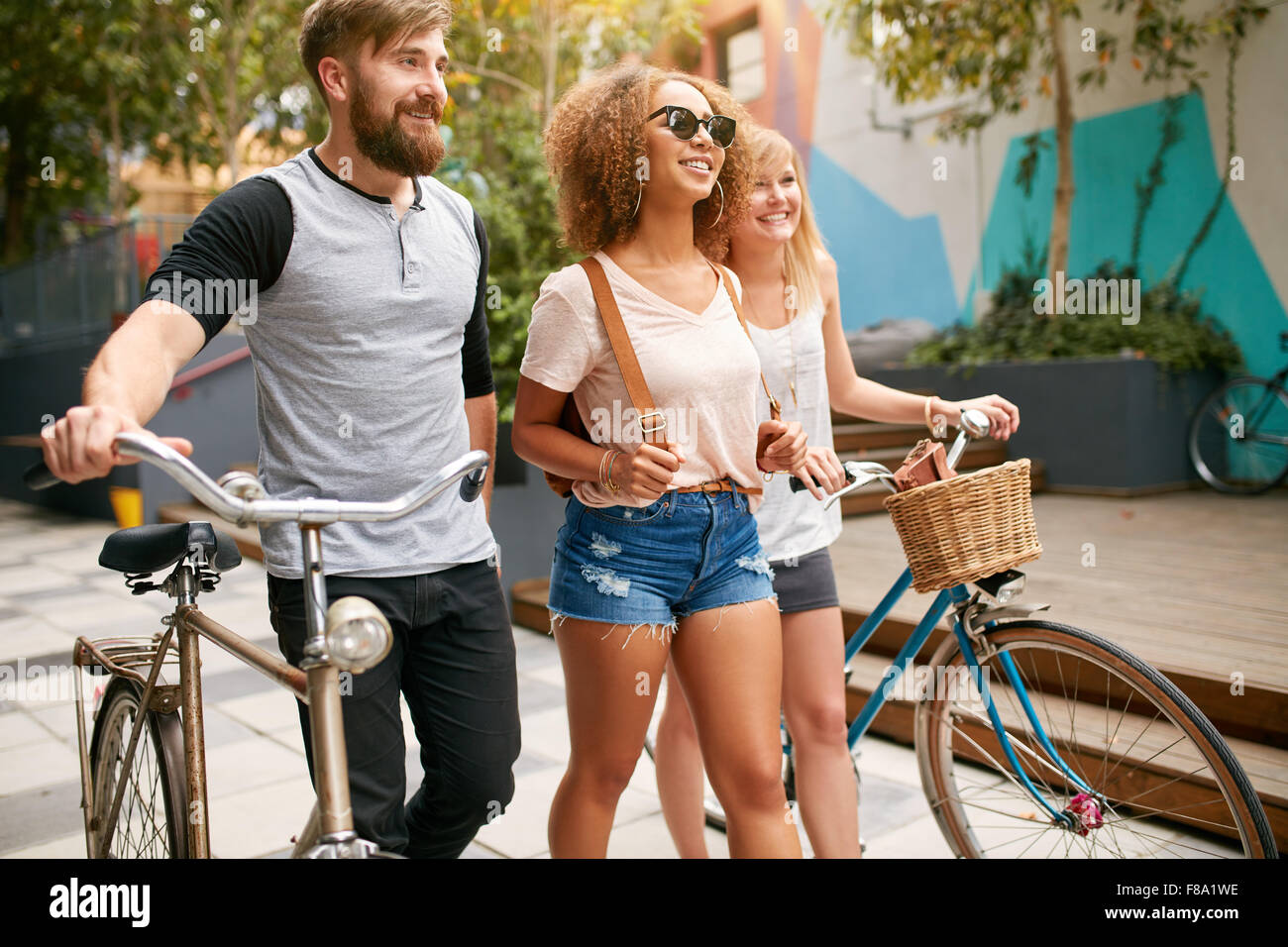 Im Freien Schuss von jungen Menschen zu Fuß auf Stadtstraße mit ihren Bikes. Drei Freunde mit Fahrrädern pro Straße. Stockfoto