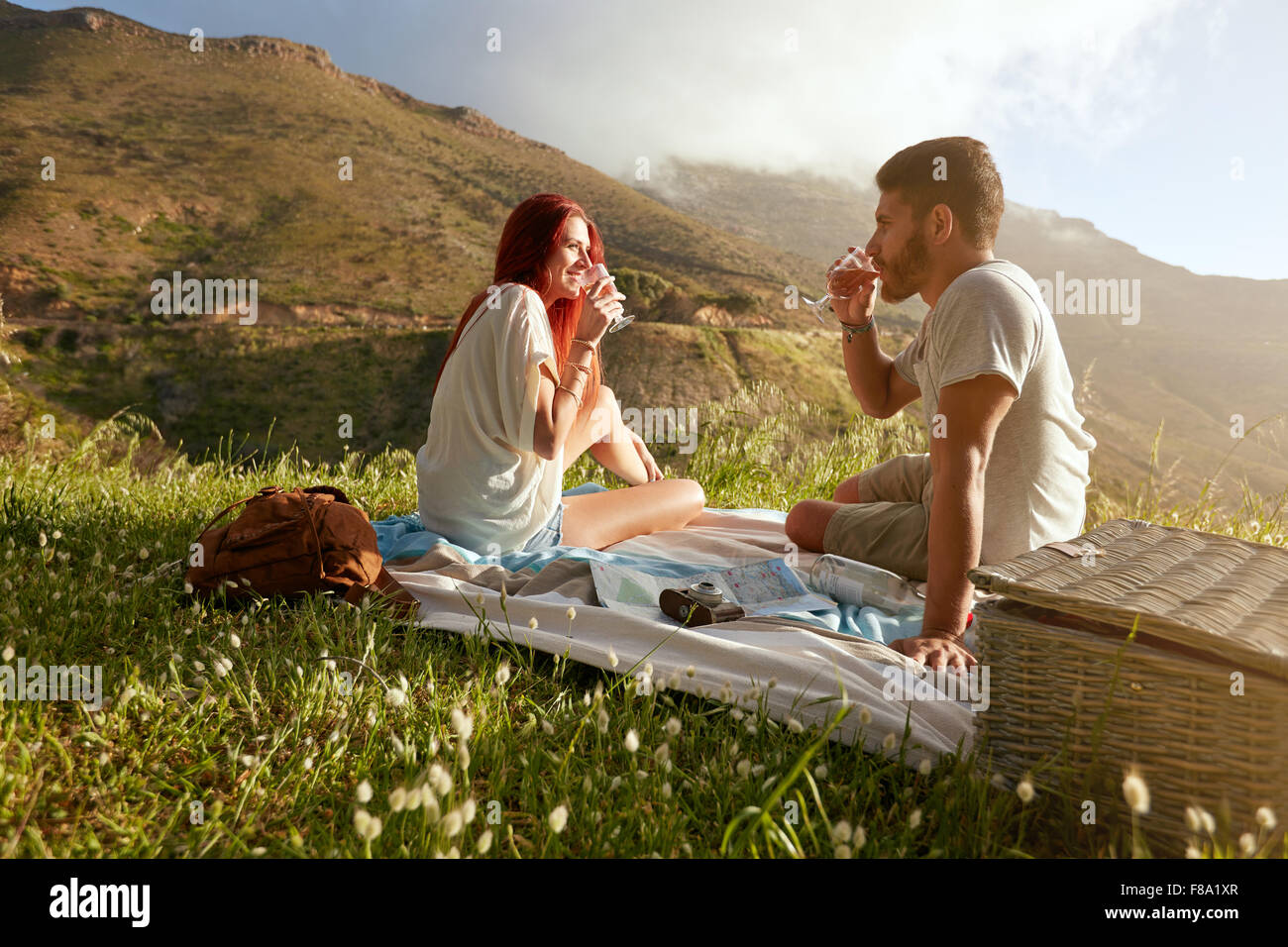 Im Freien Schuss eines jungen Paares, Wein zu trinken. Entspannter Mann und Frau in den Sommerferien in Landschaft. Stockfoto