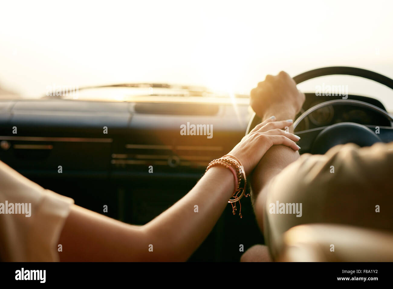Rückansicht eines jungen Paares, die Hand in Hand beim Sitzen in ihrem Auto zusammen. Mann und Frau auf einem Roadtrip. Stockfoto