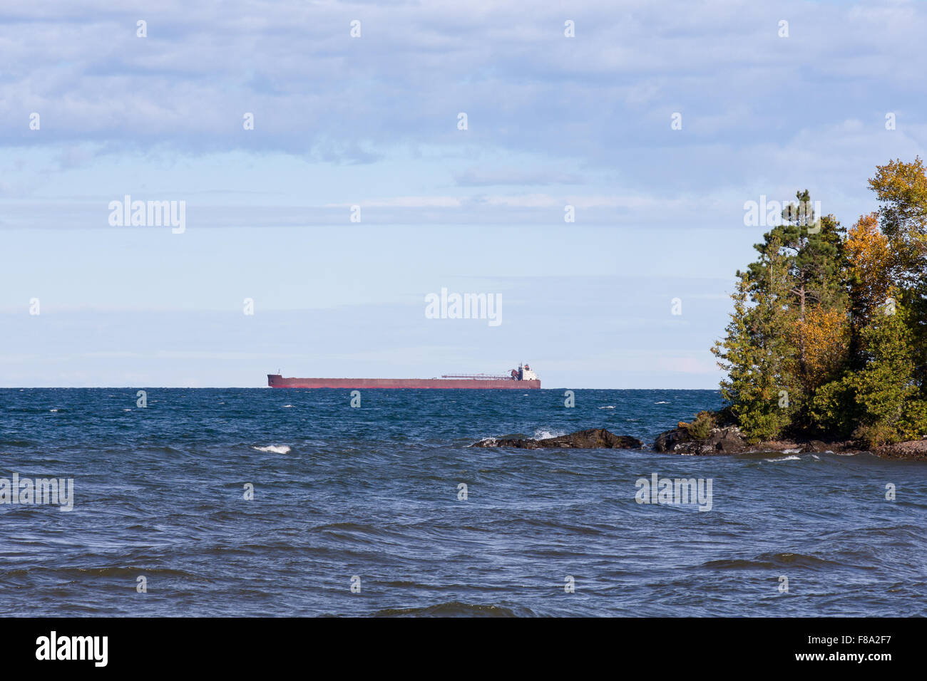 Great Lakes Paddel Boot am Horizont vorbei hinter einer felsigen Insel mit Bäumen.  Tief hängenden Wolken und viel Platz für die Kopie. Stockfoto