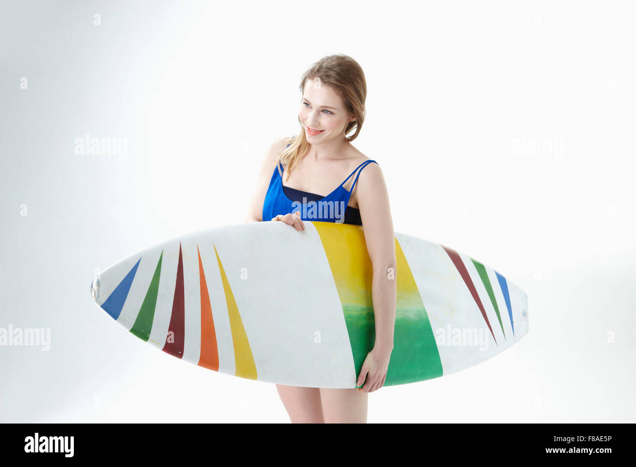 Lächelnde Dame mit einem Surf-Board unter dem Arm holding Stockfoto