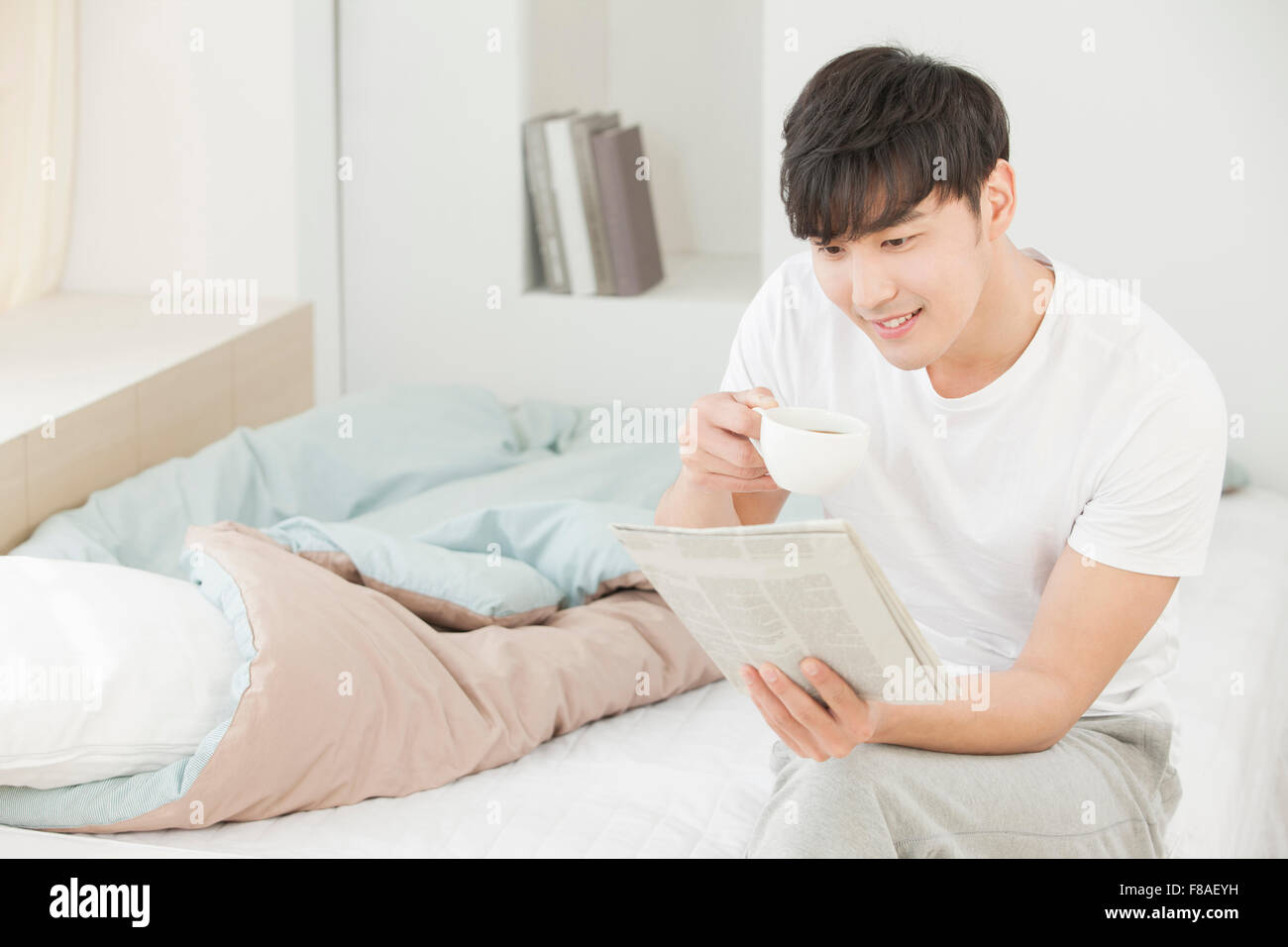 Mann hält eine Tasse und Zeitung lesen Stockfoto