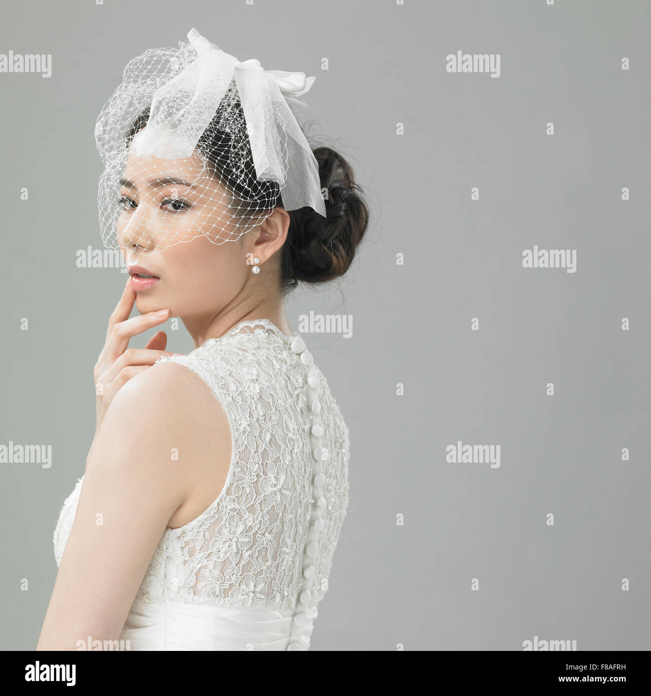 Frau in Hochzeit Kleid und Haar Band mit der Hand am Kinn Stockfoto