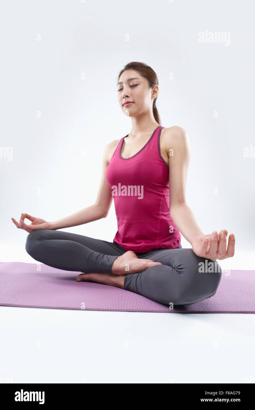 Frau mit Augen geschlossen sitzen auf Yoga-Matte Stockfoto