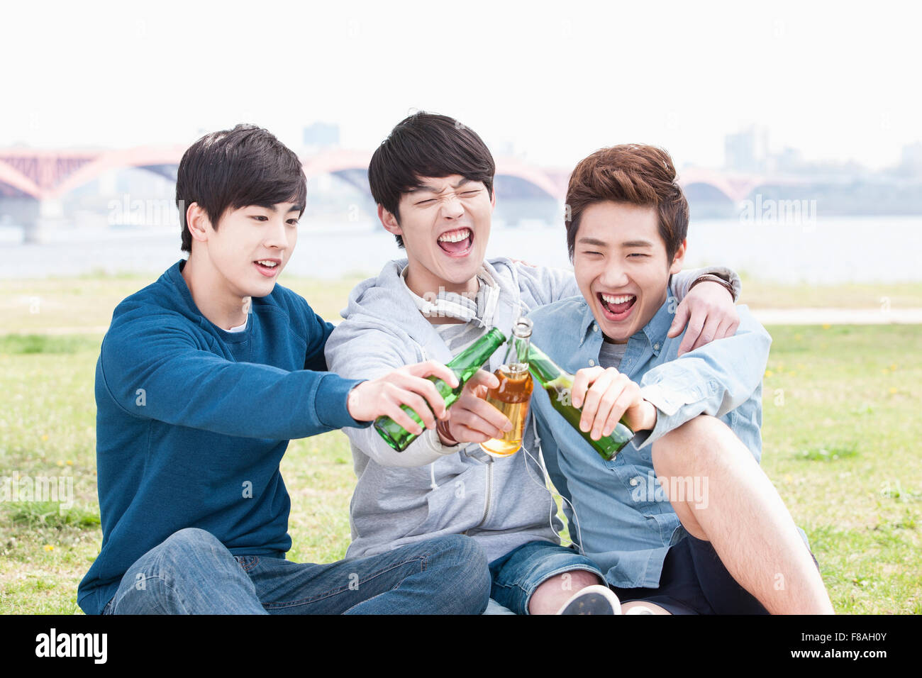 Drei Männer setzen ihre Arme um die Schultern und Toasten mit Bier Stockfoto