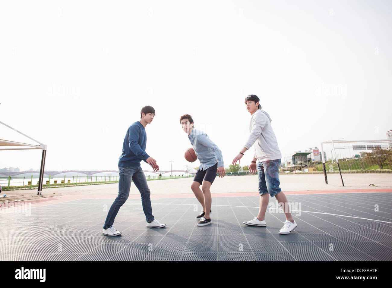 Drei Männer spielen einen Basketball auf dem Basketballplatz Stockfoto