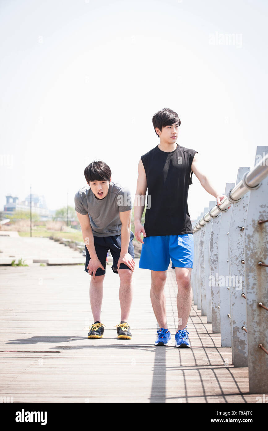 Zwei junge Männer in der Sportswear eine Pause in der Nähe von den Zaun am Flussufer des Han River park Stockfoto