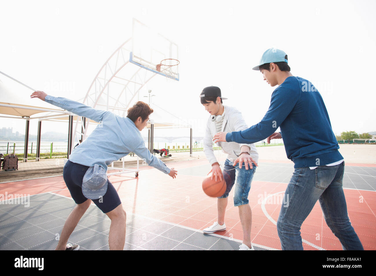 Drei junge Männer am Hof Basketball spielen Stockfoto