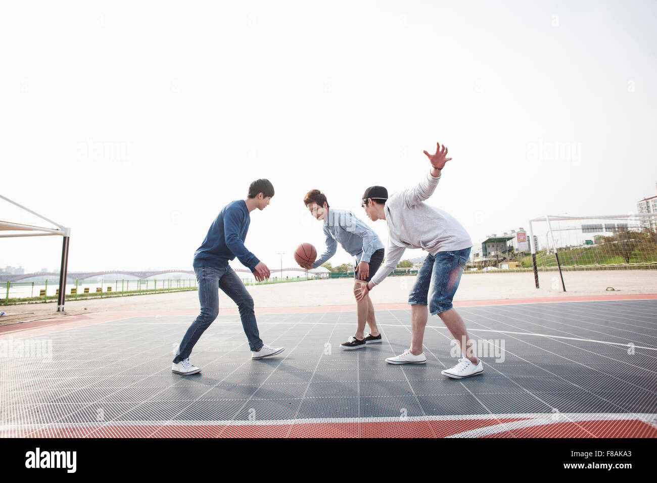 Drei junge Männer Basketball aktiv am Hof zu spielen Stockfoto