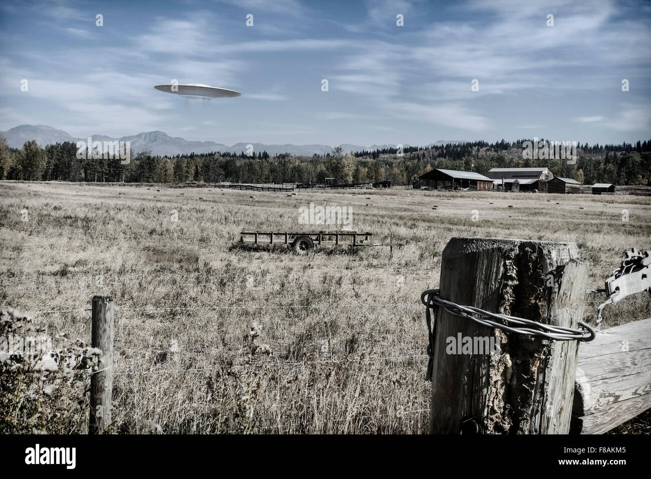 UFO fliegt über Ackerland mit Gebäuden im Hintergrund eingefärbt für einen Vintage-Look. Stockfoto