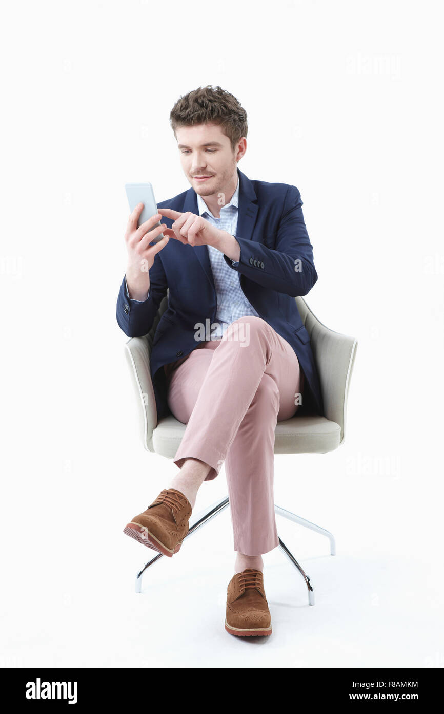Geschäftsmann, sitzen auf Stuhl mit gekreuzten Beinen und Smartphone halten und berühren Stockfoto