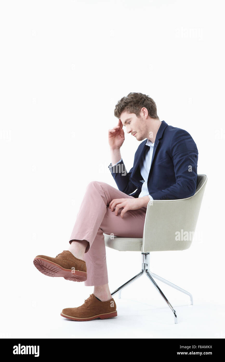 Stressigen Geschäftsmann auf Stuhl sitzend mit seinem Bein gekreuzt Stockfoto