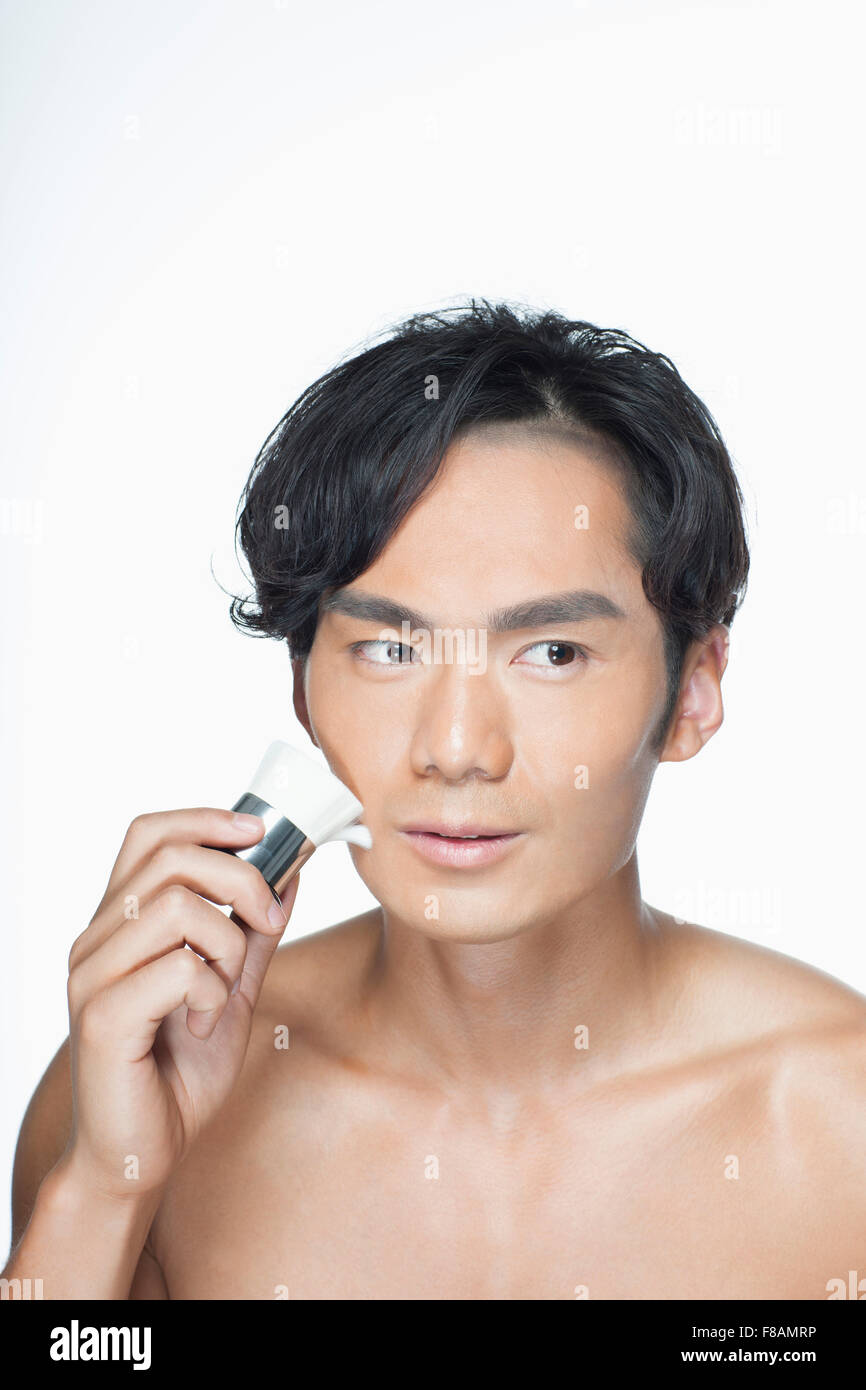 Porträt von asiatischer Mann reibt sein Gesicht mit einem Pinsel Stockfoto