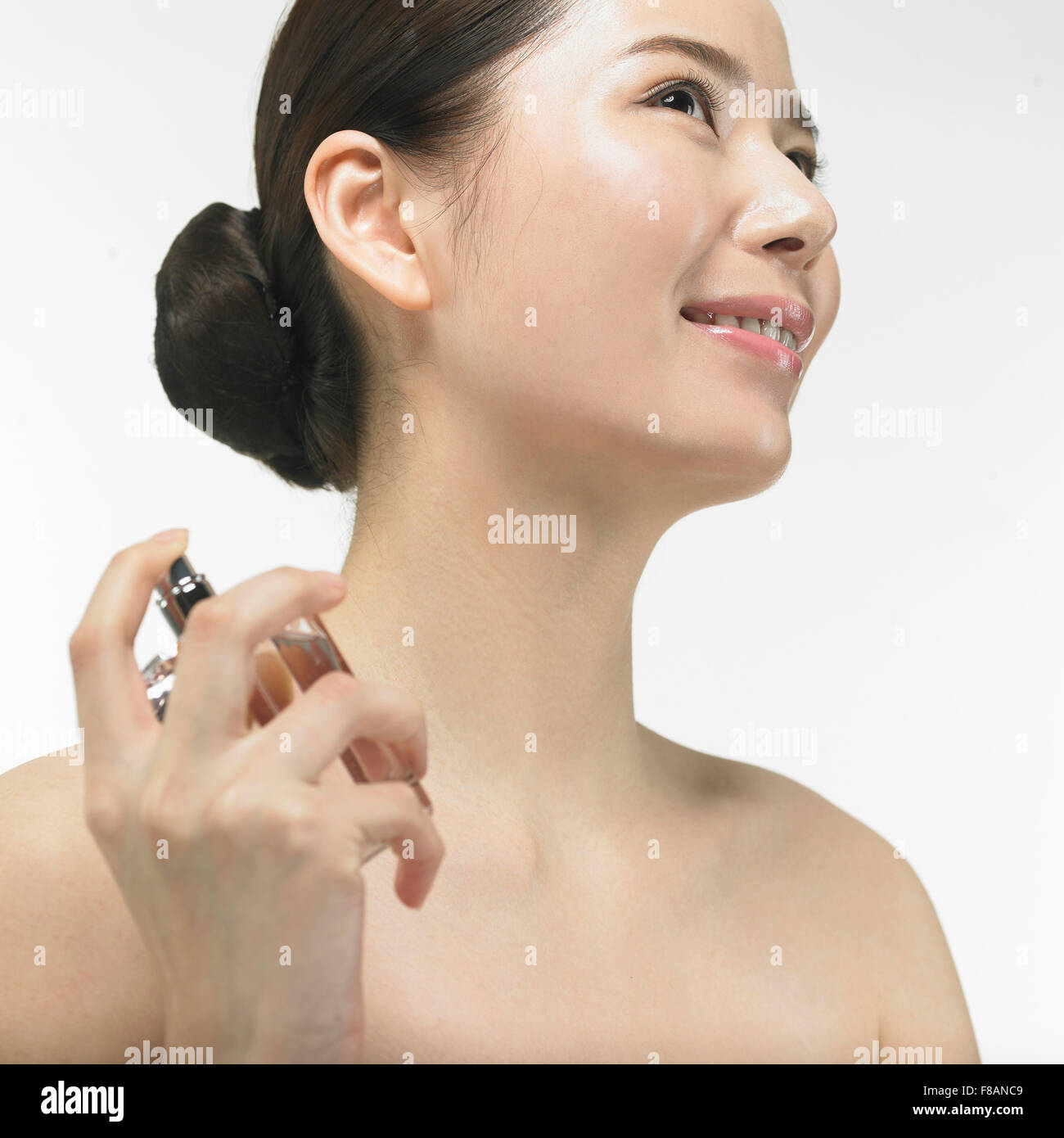 Seite Ansicht Porträt des lächelnden Koreanerin mit Haar Tie-up sprühen Parfüm Stockfoto