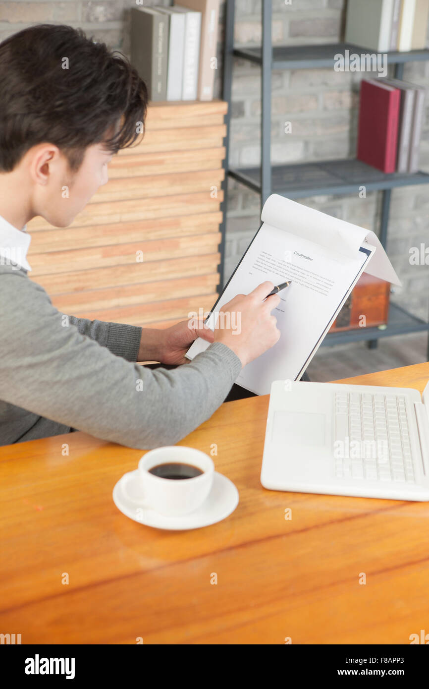 Seite Ansicht Porträt jungen Geschäftsmann hält einen Stift und Papier im Café lesen Stockfoto